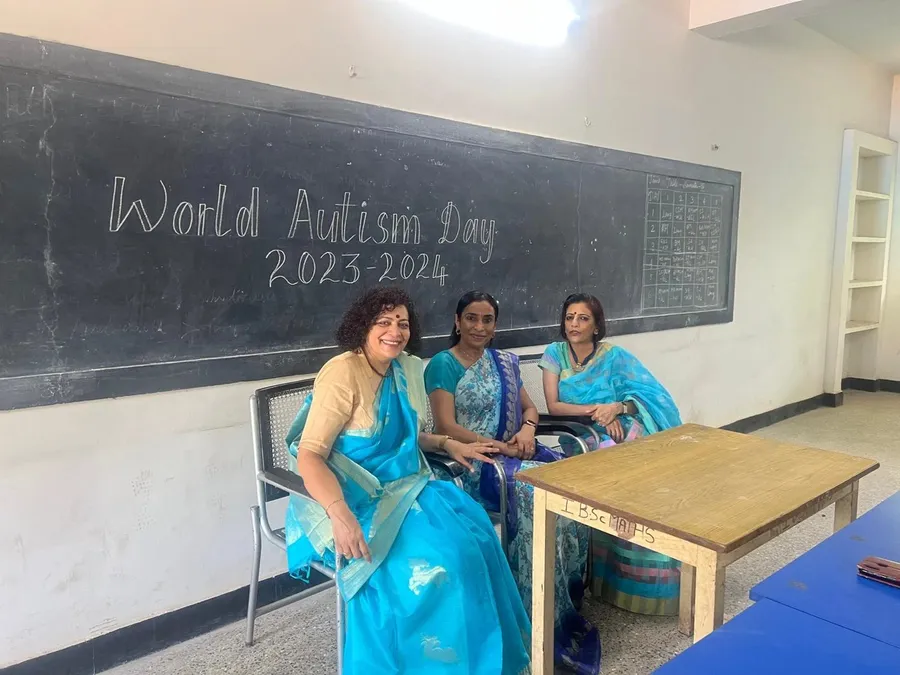 Three women seated in front of a blackboard that reads World Autism Day 2023-2024